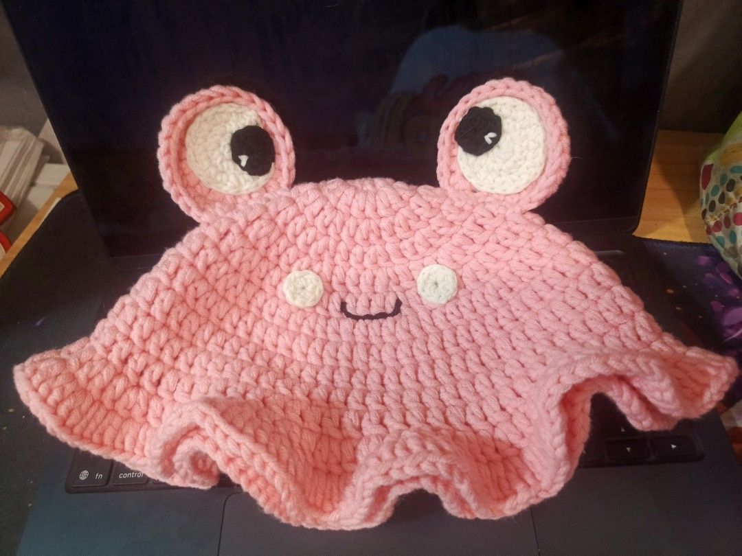 Crochet Pink Frog Bucket Hat (Category: Hats & Beanies) located in Pasig City. Submitted by ohdeepee13 (Listing ID 1466476797, Image 2). Description: 📦 Ready to ship 👒Free size - Handmade crochet bucket hat in soft pastel pink - Features cute 3D frog eyes, white cheek circles, and a stitched smiley mouth - Flared wavy brim style for a trendy look - Made from soft, lightweight, and stretchy yarn for a comfortable fit - Clean stitches and crafted