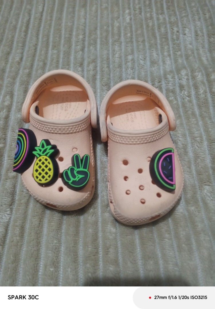 Crocs Classic Clogs Kids Size C4 Peach With Jibbitz (Category: Babies & Kids Fashion) located in Muntinlupa City. Submitted by bravedolphin.c112ad (Listing ID 1466428932, Image 1). Description: - Size: Toddler C4 - Color: Peach - Includes attached Jibbitz: Pineapple, watermelon, rainbow, peace sign - Features: Slip-on design with secure pivoting heel strap and Iconic Crocs comfort insoles - Condition: Light dirt on soles from previous wear, other