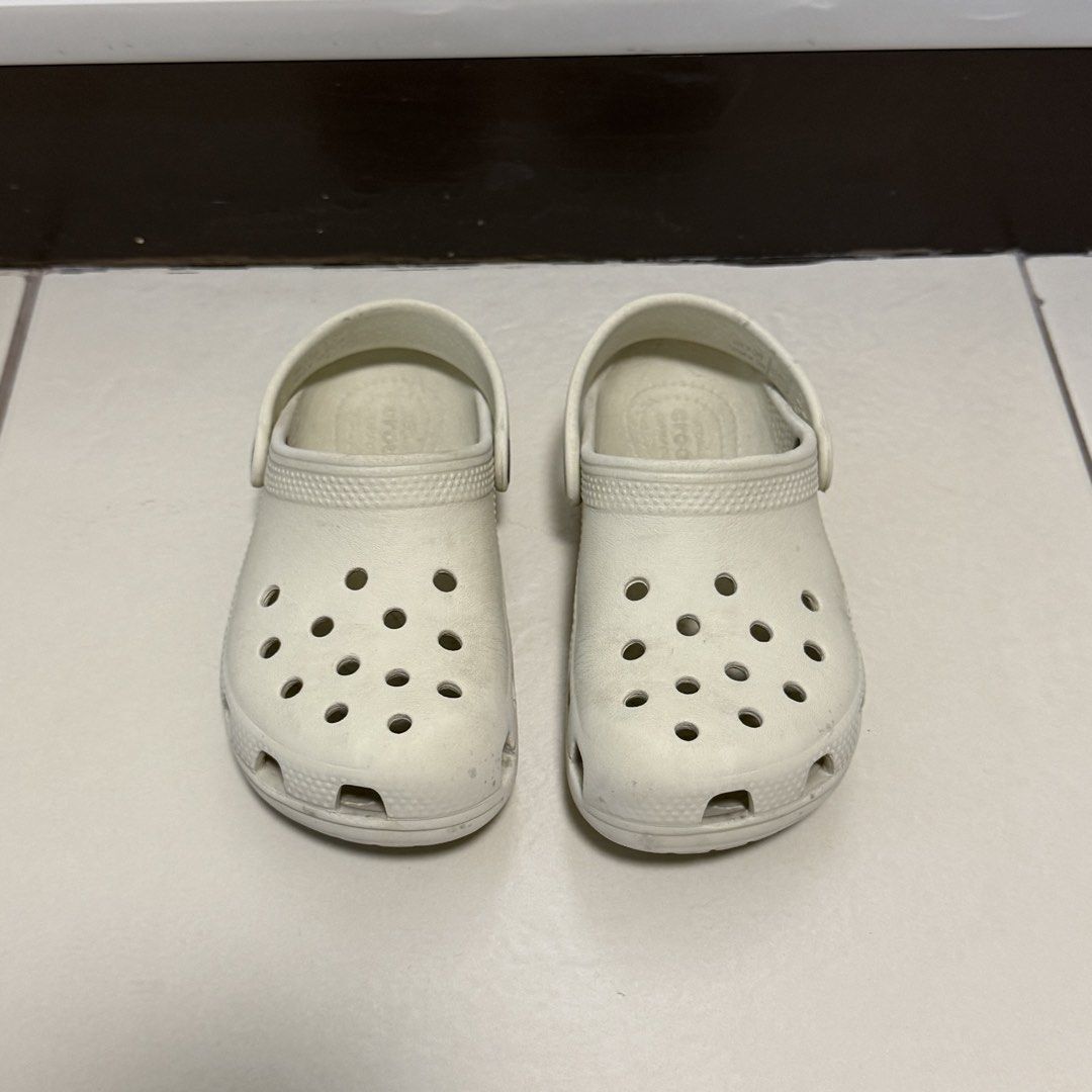 Crocs Classic Clogs Off White Size C12 (Category: Babies & Kids Fashion) located in Taguig. Submitted by lessthangel_ (Listing ID 1465224232, Image 2). Description: - Item: Crocs Classic Clogs - Color: Bone / Off-White - Size: C12 (Kids) - Design: Slip-on with ventilation ports and pivoting heel strap - Condition: Pre-loved with moderate scuffs and dirt marks from daily wear - Perfect for daily casual wear, playground, or beach trips -Not thrifte