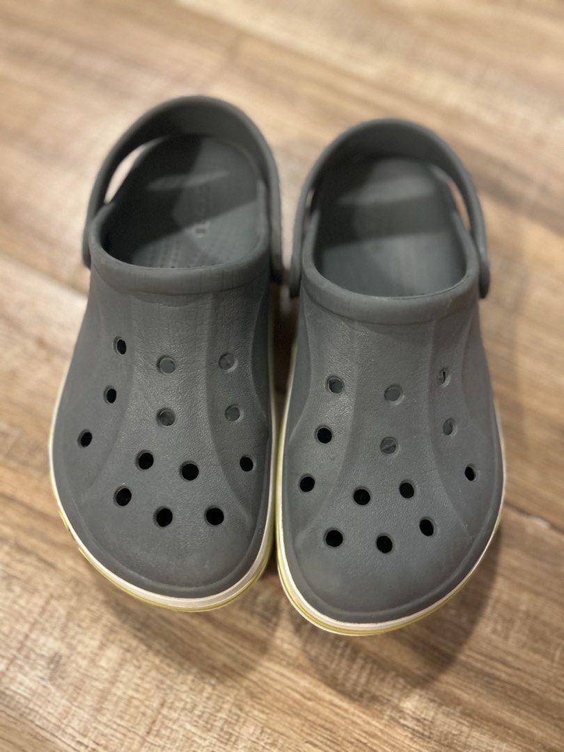 Crocs Crocband Clogs Grey Kids Size J1 (Category: Babies & Kids Fashion) located in San Fernando. Submitted by gisellelynn77 (Listing ID 1466562273, Image 2). Description: - Authentic Kids Crocs Crocband Clogs - Color: Grey with white and yellow midsole stripe - Size: J1 - Condition: Excellent, minimal wear on soles with fully intact tread - Features: Ventilation holes, pivoting heel strap, and iconic side logo - Easy to wash, quick-drying, and s