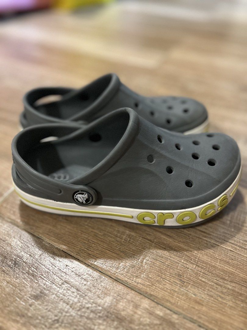 Crocs Crocband Clogs Grey Kids Size J1 (Category: Babies & Kids Fashion) located in San Fernando. Submitted by gisellelynn77 (Listing ID 1466562273, Image 3). Description: - Authentic Kids Crocs Crocband Clogs - Color: Grey with white and yellow midsole stripe - Size: J1 - Condition: Excellent, minimal wear on soles with fully intact tread - Features: Ventilation holes, pivoting heel strap, and iconic side logo - Easy to wash, quick-drying, and s