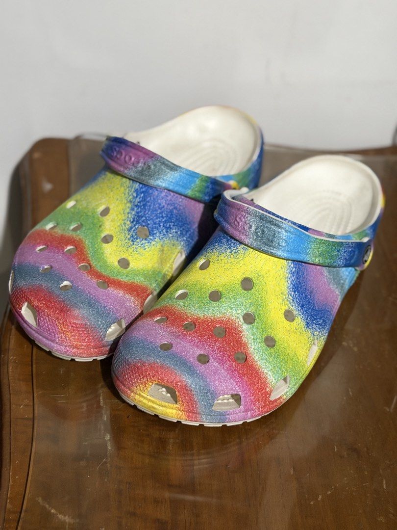 Crocs Tie Dye Classic Clogs Rainbow Colorful (Category: Slippers and slides) located in Pasig City. Submitted by momfinds23 (Listing ID 1466529850, Image 3). Description: -Size M12 - Vibrant rainbow tie-dye design featuring blues, yellows, greens, reds, and purples - Classic slip-on style with breathable ventilation holes across the upper - Secure pivoting heel straps for a versatile fit - Lightweight and comfortable foam construction - Easy to c