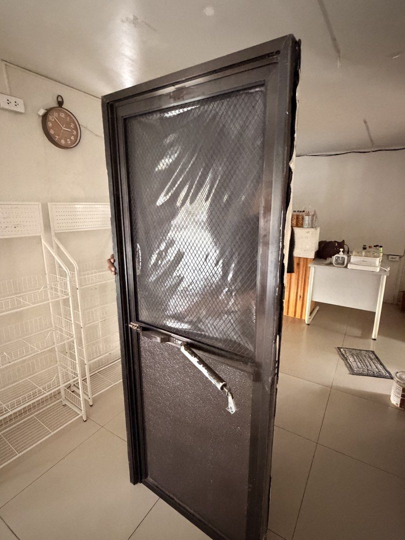 Dark Brown Screen Door with Mesh and Handle (Category: Locks, Doors & Gates) located in Mandaluyong City. Submitted by classymissy014 (Listing ID 1466516778, Image 1). Description: - Heavy-duty metal frame construction in dark brown - Upper wire mesh section for ventilation - Solid lower panel for added durability - Includes handle hardware and middle closing mechanism - Standard single door size 70x180 - Clean and ready for immediate installatio