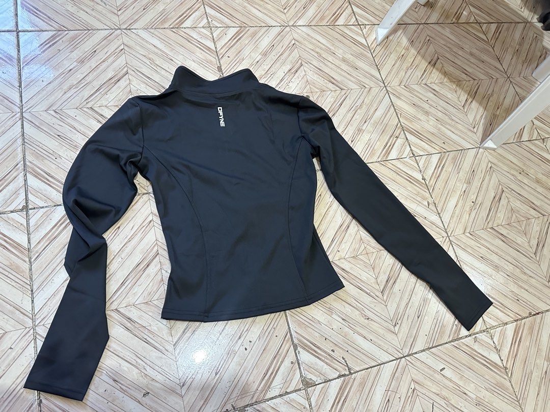 DFYNE Black Activewear Zip Jacket Asian M (Category: Coats, Jackets and Outerwear) located in Angeles City. Submitted by alejeong27 (Listing ID 1466428375, Image 3). Description: DFYNE athletic jacket in black. Full front zipper with high neck collar. White branding on the front chest and back neck area. Long sleeves with thumb holes. Material label reads Asian M, composed of 83% polyester and spandex blend. Slim fit design, good for workouts or 