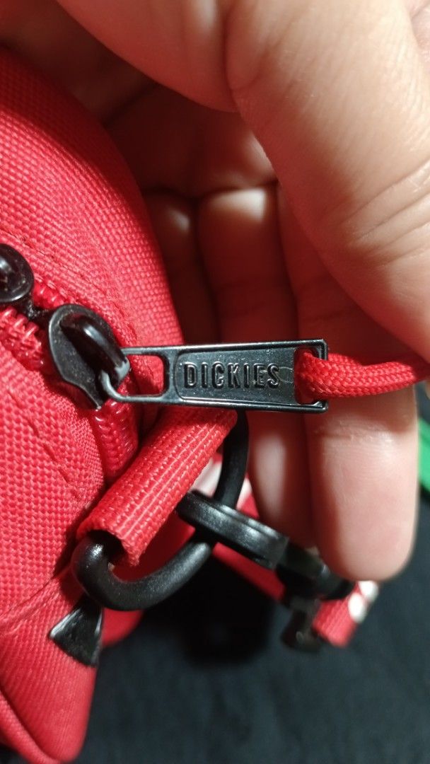 Dickies Red Crossbody Bag (Category: Sling Bags) located in Manila. Submitted by zariyah.1986 (Listing ID 1466475913, Image 3). Description: - Brand: Dickies - Color: Bright red with white embroidered logo - Material: Clean, sturdy canvas - Compartments: Zippered main compartment and handy front zipper pocket - Strap: Adjustable red strap with repeat Dickies branding - Interior: Dark lining with branded stamp - Condition: Great compact size for d