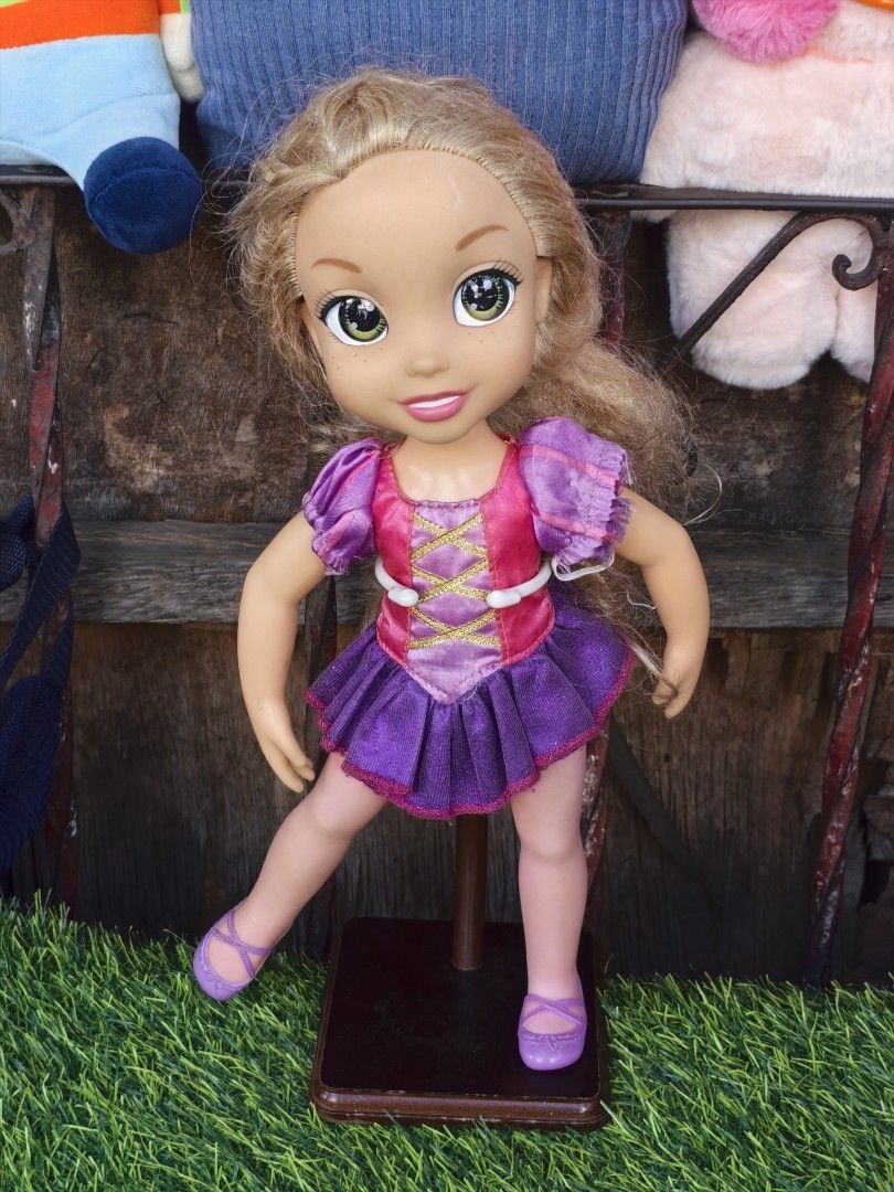 Disney Rapunzel Doll Jakks Pacific (Category: Kids Toys) located in Paranaque City. Submitted by furugiyafinds (Listing ID 1466351518, Image 2). Description: - Authentic Disney Rapunzel doll by Jakks Pacific - Wears her classic purple and pink dress - Features lovely blonde hair, green eyes, and cute freckles - Includes a brown display stand as seen in photos - Great addition for Disney fans and collectors - Condition: Excellent / Well-kept - Mod