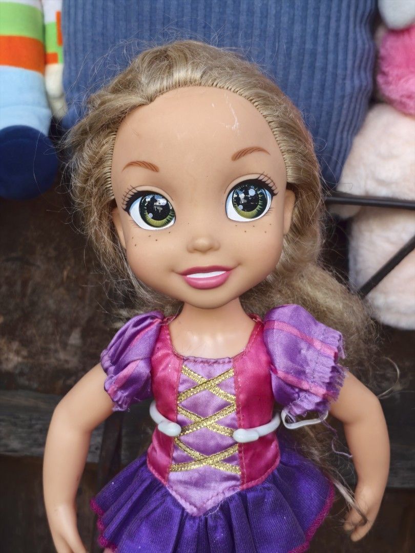 Disney Rapunzel Doll Jakks Pacific (Category: Kids Toys) located in Paranaque City. Submitted by furugiyafinds (Listing ID 1466351518, Image 1). Description: - Authentic Disney Rapunzel doll by Jakks Pacific - Wears her classic purple and pink dress - Features lovely blonde hair, green eyes, and cute freckles - Includes a brown display stand as seen in photos - Great addition for Disney fans and collectors - Condition: Excellent / Well-kept - Mod