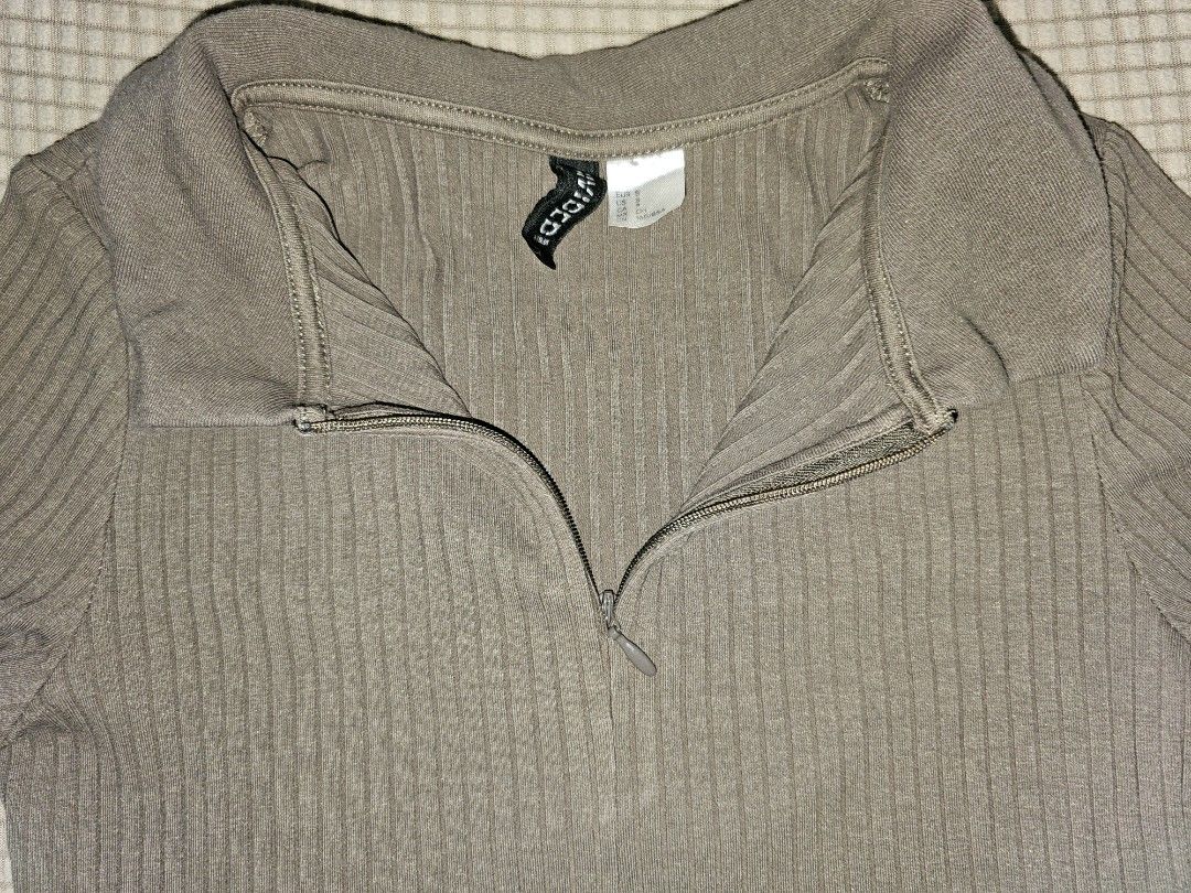 Divided H&M Ribbed Zip-Up Collared Crop Top (Category: Sleeveless) located in Marikina City. Submitted by lacheriecloset (Listing ID 1466468629, Image 2). Description: Divided by H&M crop top in a brownish-grey shade. Ribbed knit material with short sleeves and a collared neckline. Front features a quarter zip closure. Size S tag attached inside the collar. Simple everyday basic top, easy to style with high-waisted jeans or skirts..