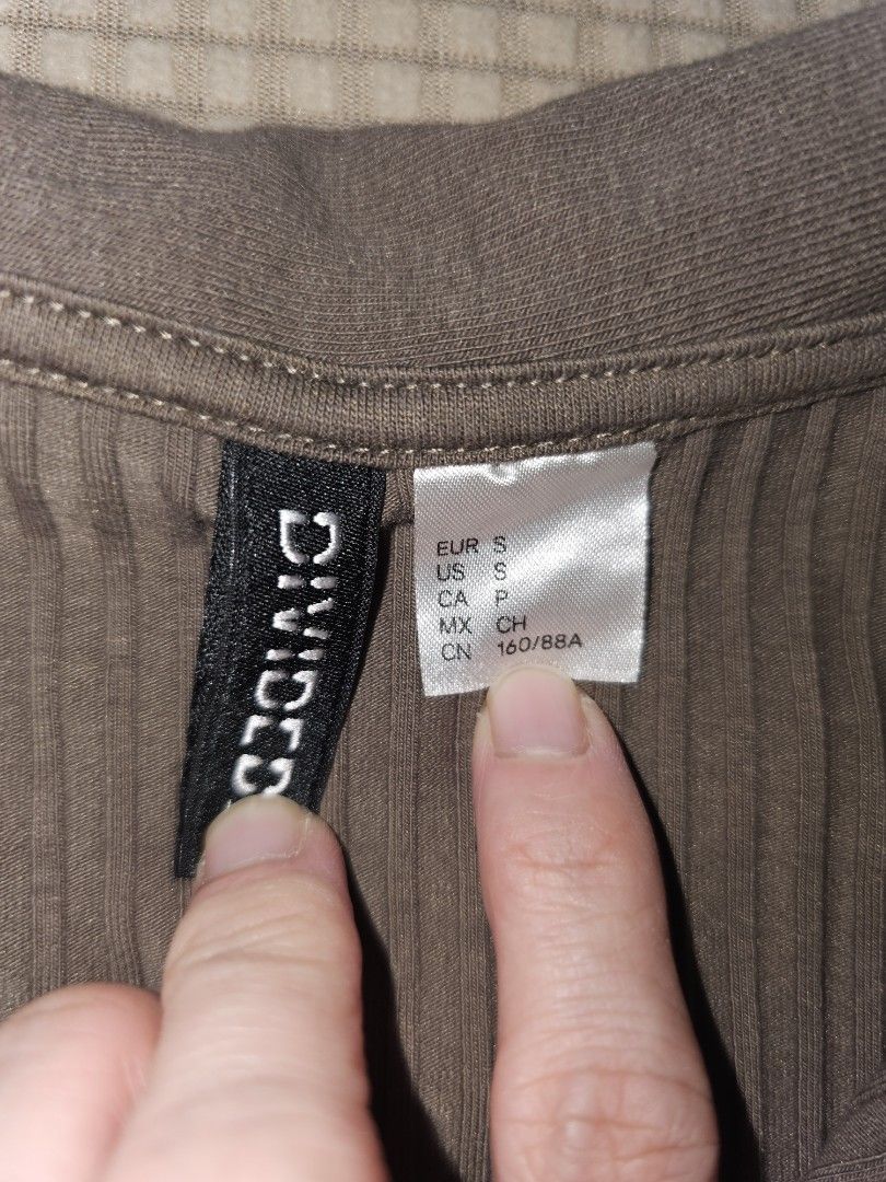 Divided H&M Ribbed Zip-Up Collared Crop Top (Category: Sleeveless) located in Marikina City. Submitted by lacheriecloset (Listing ID 1466468629, Image 3). Description: Divided by H&M crop top in a brownish-grey shade. Ribbed knit material with short sleeves and a collared neckline. Front features a quarter zip closure. Size S tag attached inside the collar. Simple everyday basic top, easy to style with high-waisted jeans or skirts..