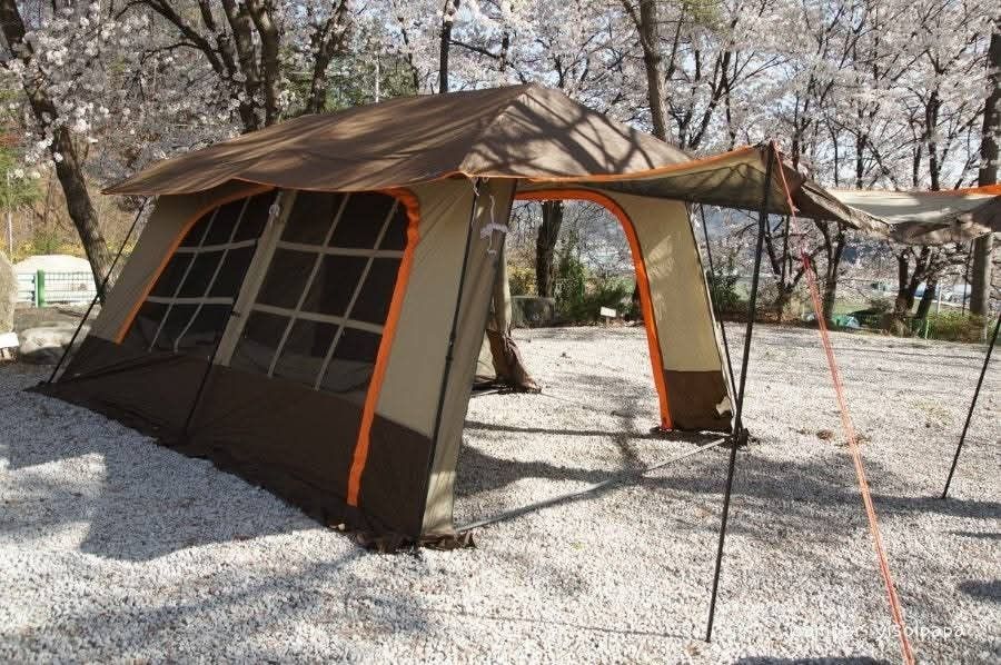 Family Camping Tent (Category: Hiking & Camping) located in Abucay. Submitted by cristineca20489 (Listing ID 1466557326, Image 3). Description: Spacious camping tent with brown and tan exterior tones. Multiple mesh window panels provide great ventilation throughout. Integrated awning creates a nice shaded outdoor seating space right at the front entrance. Heavy-duty poles and guy lines keep the whole setup completely stable on gravel or dirt grou