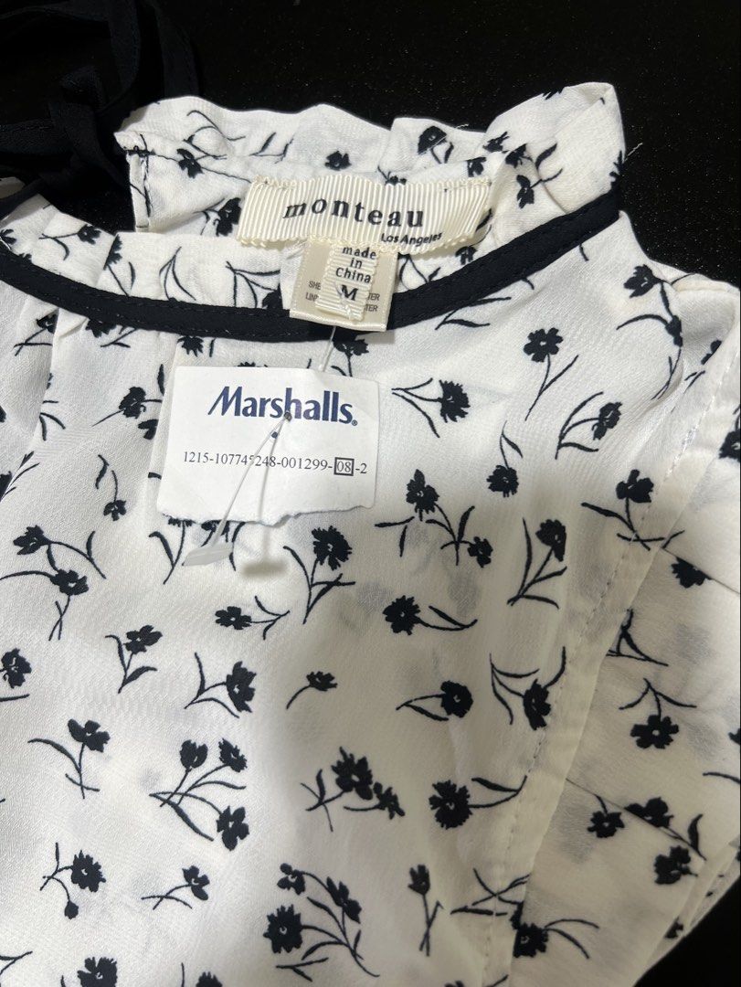 Floral Short Sleeve Blouse (Category: Blouses) located in Pasig City. Submitted by jsyrgt (Listing ID 1466430978, Image 3). Description: White Floral Blouse Condition: 10/10 Brand New with Marshalls store tag attached. Small yellowish stain on the side seam near the armhole area (shown in the last photo). Design: High neckline trimmed in black, open back with a black tie closure Details: Floral print blouse with short flutter sleeves Styling: Gre