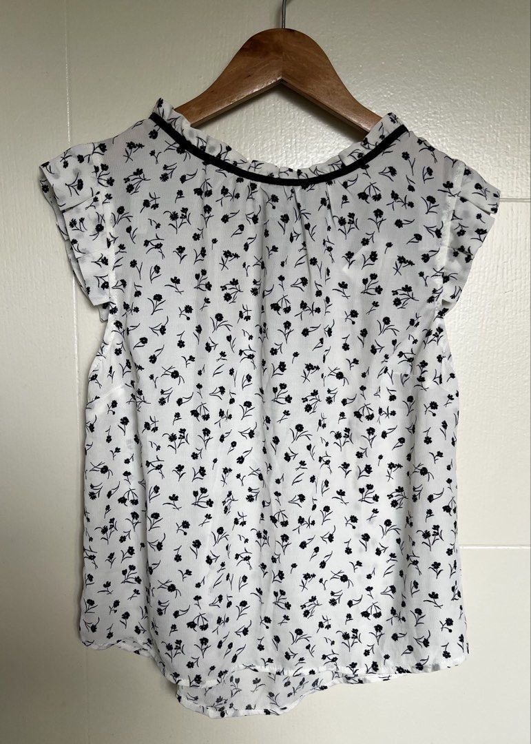 Floral Short Sleeve Blouse (Category: Blouses) located in Pasig City. Submitted by jsyrgt (Listing ID 1466430978, Image 1). Description: White Floral Blouse Condition: 10/10 Brand New with Marshalls store tag attached. Small yellowish stain on the side seam near the armhole area (shown in the last photo). Design: High neckline trimmed in black, open back with a black tie closure Details: Floral print blouse with short flutter sleeves Styling: Gre