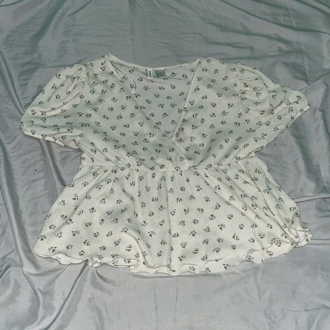 Floral V-neck Peplum Blouse (Category: Blouses) located in Makati City. Submitted by kaiii.25 (Listing ID 1466420678, Image 1). Description: - Design: White fabric with delicate blue and green floral print - Cut: V-neck wrap front with a flared peplum waist and ruffled hem - Sleeves: Trendy short puff sleeves - Fabric: Textured, super lightweight, and comfortable - Fit: True to size, easy to mix and match - Can still lower the price.
