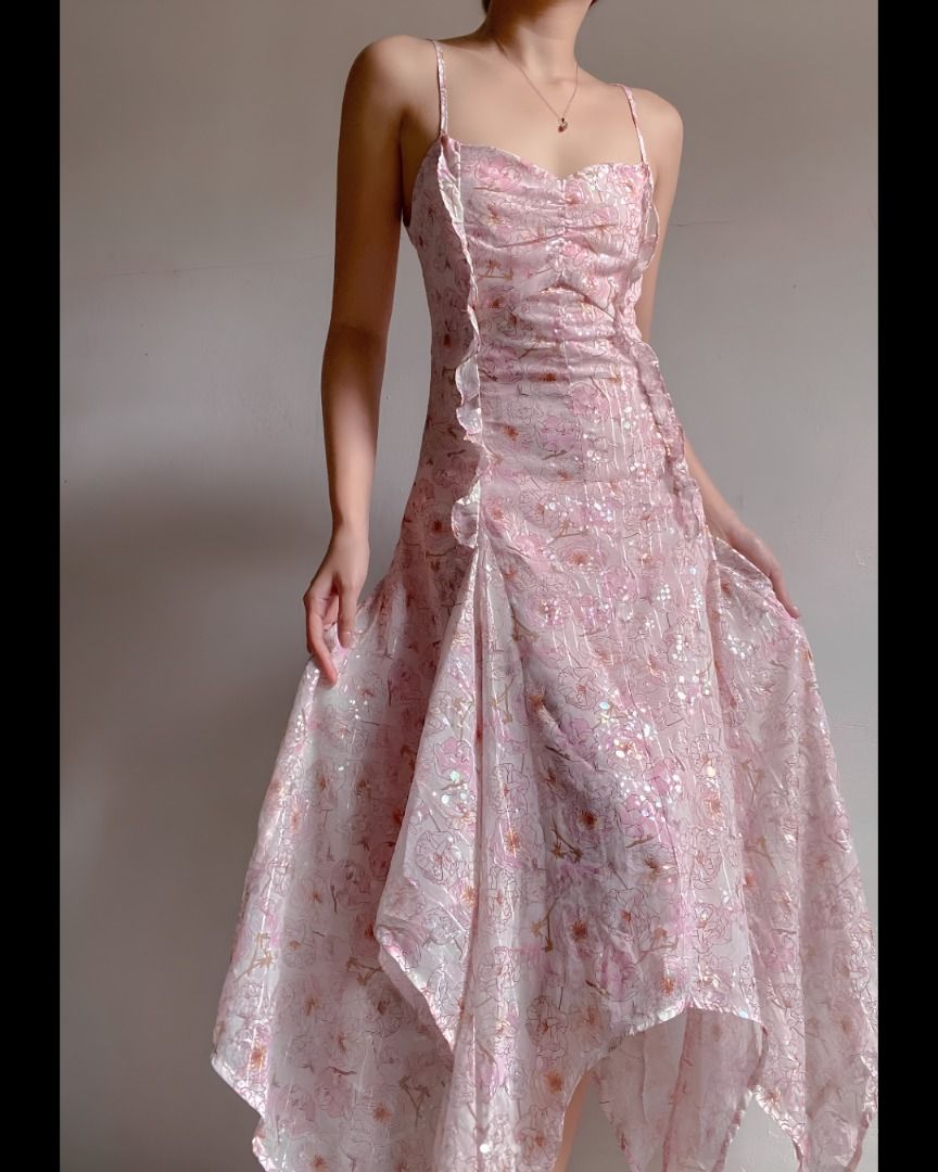 Flowy ruffle dress (Category: Dresses) located in Pasig City. Submitted by aelena._ (Listing ID 1466459193, Image 3). Description: Fits s Bust: 30-32” Waist: 25-27” Length: 48” - Color & Style: Pink midi dress with a subtle floral pattern and iridescent sheen - Neckline & Straps: Sweetheart neckline with a ruched center and delicate spaghetti straps - Details: Cascading front ruffles and a trendy asymmetrical handkerchief hemline - Fit: Body-hugg