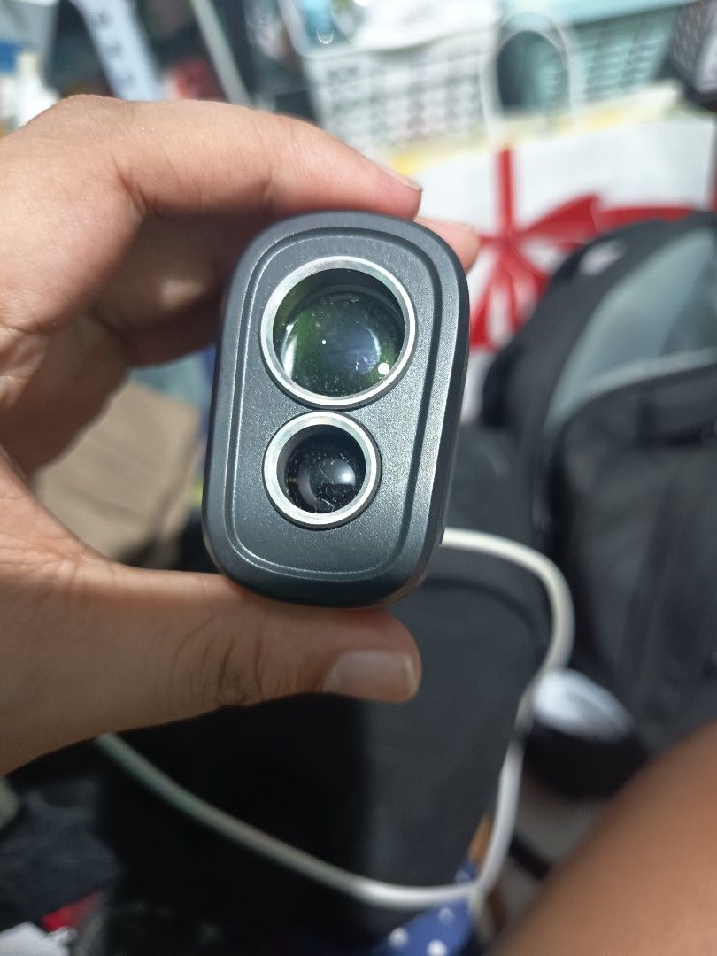 FossiBOT C1000F Laser Rangefinder 3-1000M (Category: Golf) located in Manila. Submitted by lord_setzer01 (Listing ID 1466468554, Image 3). Description: FossiBOT C1000F laser rangefinder measuring up to 1000M. Black body with bright yellow accent lines along the sides. Dual lens setup on the front for target acquisition. Standard focus ring near the eyepiece. Charging via cable with a visible red indicator light next to the port. Compact size, eas