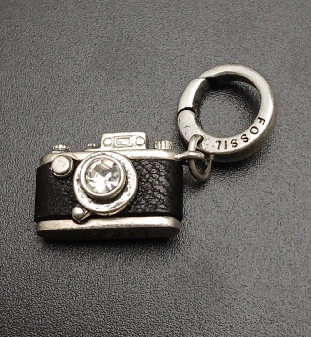 FOSSIL Authentic Camera Charm (Category: Charms) located in Calapan. Submitted by shakalak (Listing ID 1466354093, Image 1). Description: - Authentic Fossil mini camera charm - Silver-tone metal with black textured leather detail - Sparkling clear rhinestone set in the lens - Includes branded clip ring and top clasp attachment - Versatile accessory for bags, bracelets, or keychains-Was 1999.