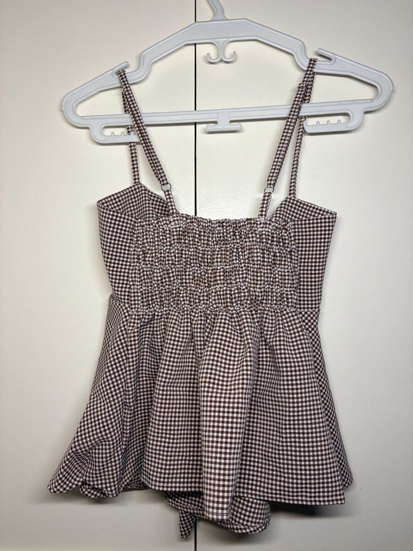 Gingham Tie-Front Cami Top (Category: Others Tops) located in Paranaque City. Submitted by honeykkkk (Listing ID 1466476881, Image 2). Description: • Details: Classic brown and white gingham/checkered print, adjustable shoulder straps, front tie-ribbon knot, a stretchy smocked back panel for a comfortable fit, and a flared peplum-style hemline. Super cute for casual, picnic, or summer outfits. • Condition: Like new — tried on once to fit, but nev