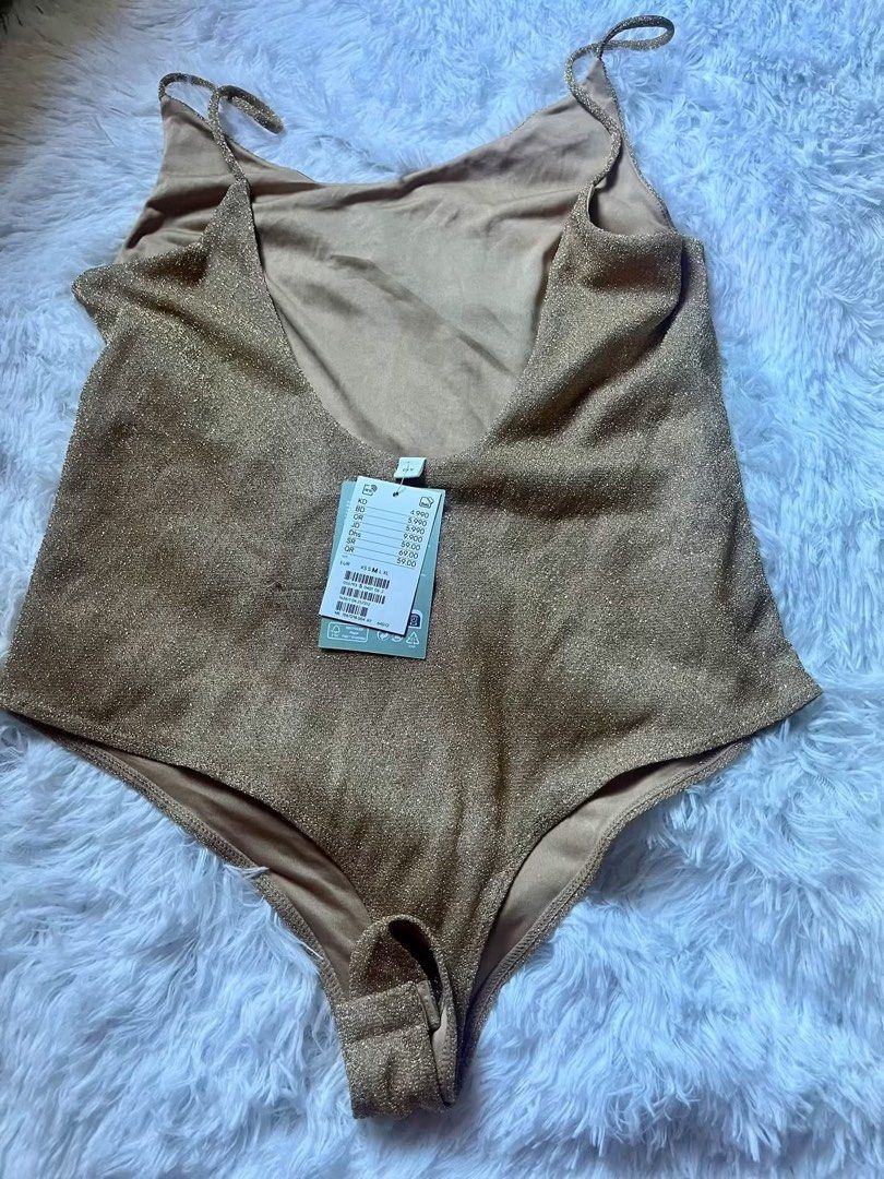 Gold glitter spaghetti strap bodysuit (Category: Sleeveless) located in Tabaco. Submitted by devskie (Listing ID 1466424913, Image 2). Description: - Brand: H&M bought in Kuwait New with tags attached (multi-currency price tag) - Size: Medium (M) - Color/Finish: Sparkly gold - Design: Thin spaghetti straps and trendy low back - Feature: Convenient snap closure at the bottom - Condition: Brand new, never worn.