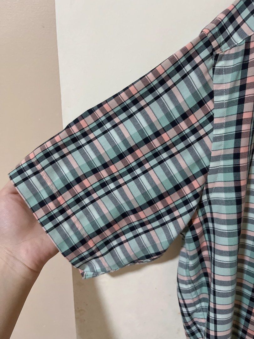 GQ plaid short sleeve button up shirt (Category: Tshirts & Polo Shirts ) located in Manila. Submitted by _preciousfinds.2 (Listing ID 1466517526, Image 3). Description: - Brand/Style: GQ short sleeve button-down shirt - Color/Pattern: Light mint green base with pink, black, and white plaid - Features: Collared neck with button-down points and front button closure - Pocket: Single left chest pocket with a small colored tab accent - Condition/Vibe: