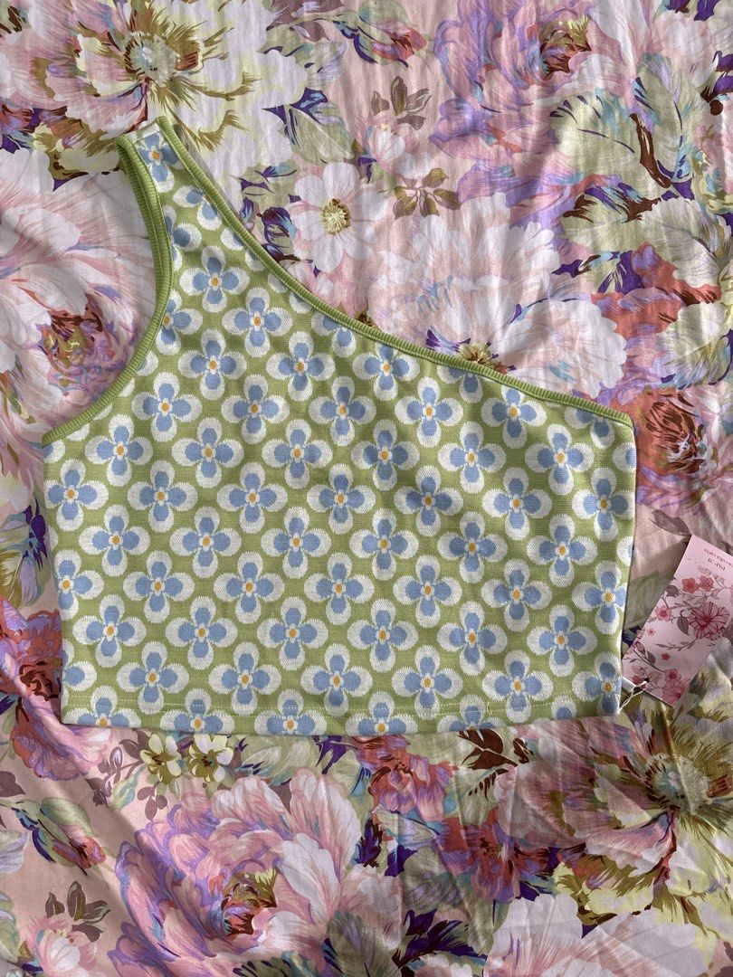 Green blue floral one shoulder crop top (Category: Sleeveless) located in Paranaque City. Submitted by delikaite (Listing ID 1466416730, Image 1). Description: - Style: One-shoulder crop top - Pattern: Retro green and blue daisy floral - Details: Ribbed trim on neckline and strap, stretchy knit fabric - Condition: Brand new with tag still attached.
