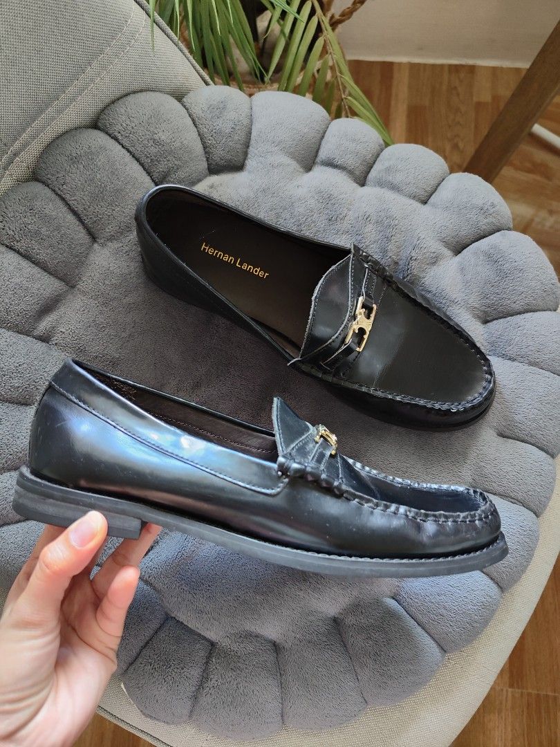 Hernan Lander Black Leather penny Loafers (Category: Loafers) located in Cavite. Submitted by itstrish23 (Listing ID 1466387620, Image 1). Description: - Brand: Hernan Lander - Color: Classic Black - Material: Premium Leather - Size: EU 35 - Style: Slip-on flat loafers with structured toe stitching - Details: Elegant gold hardware on the front strap - Condition: Good, with light scuffing on the soles underneath.