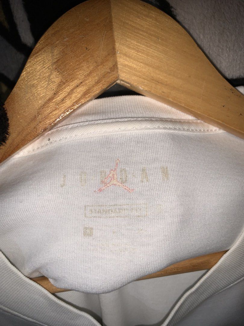 Jordan 23 Engineered White T-Shirt (Category: Tshirts & Polo Shirts ) located in Tayug. Submitted by cvcthrift (Listing ID 1466505417, Image 3). Description: 21/28 NO ISSUE EXCELLENT CR -9.5/10 - Brand: Jordan 23 Engineered - Color: White - Size: Small - Style Code: CZ5182-100 - Design: Black text graphic on chest with purple rubberized brand patch - Condition: Clean, print and patch are 100% intact with no cracks.