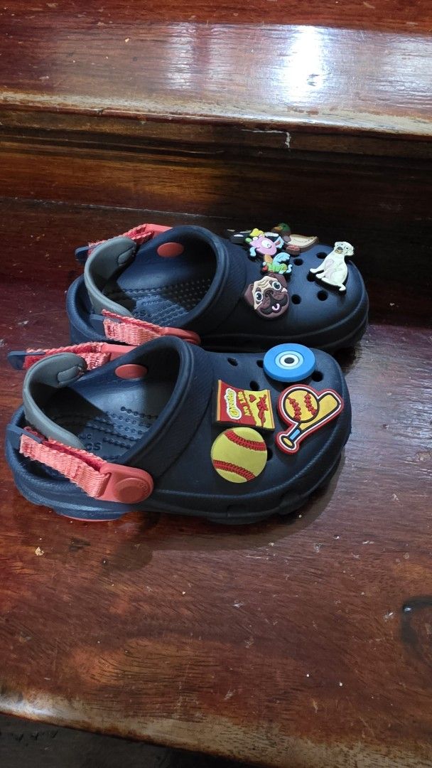 Kids Dark Navy Crocs Clogs with Jibbitz Charms (Category: Babies & Kids Fashion) located in Valenzuela. Submitted by bella_onez (Listing ID 1466445709, Image 3). Description: - Color: Dark navy toddler Crocs - Features: Adjustable straps for a secure fit - Includes: Fun Jibbitz charms (dogs, ducks, Cheetos packet, baseball gear, and evil eye) - Condition: Minor wear on bottom soles from normal use - Ideal for: Easy, everyday slip-on wear for kids