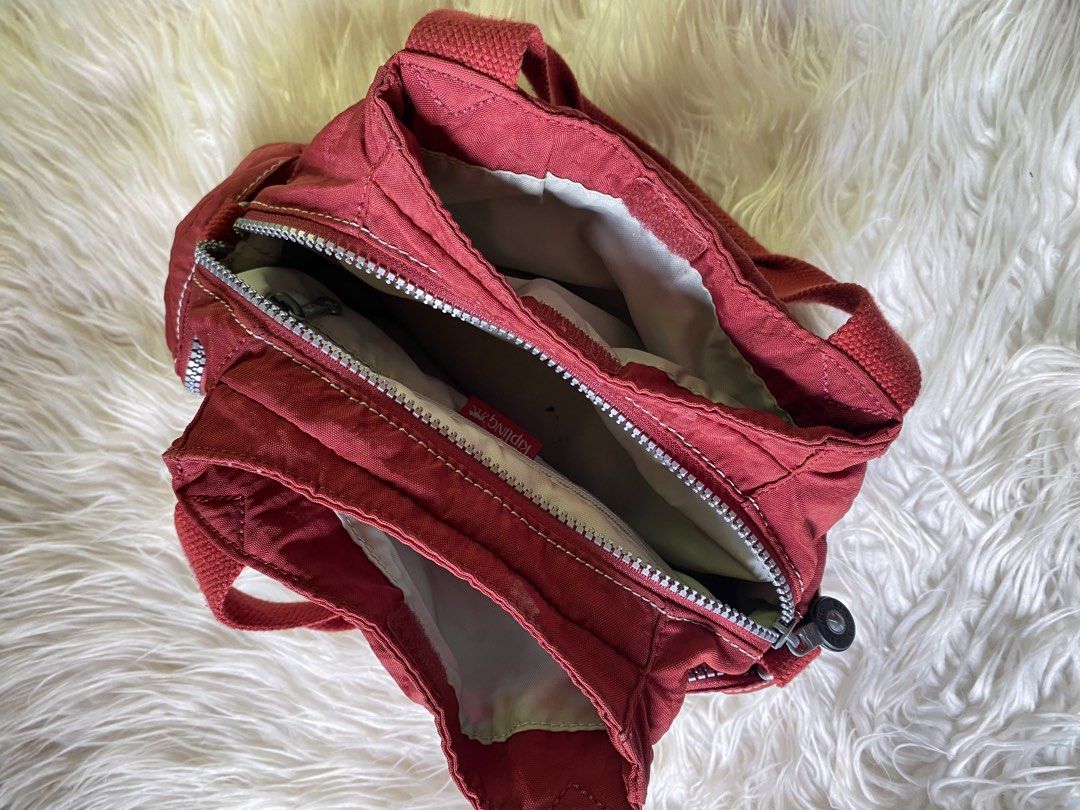 Kipling Fairfax Red Shoulder Bag K13655-108 (Category: Shoulder Bags) located in Manila. Submitted by kimberlyma95836 (Listing ID 1466412975, Image 2). Description: - Brand: Kipling - Style: Fairfax Shoulder Bag (Style Code: K13655-108) - Color: Dark Red - Material: Classic crinkle nylon with durable woven handles - Compartments: Dual main zip compartments with light grey lining - Pockets: Front flap pocket with hook-and-loop closure, plus top an