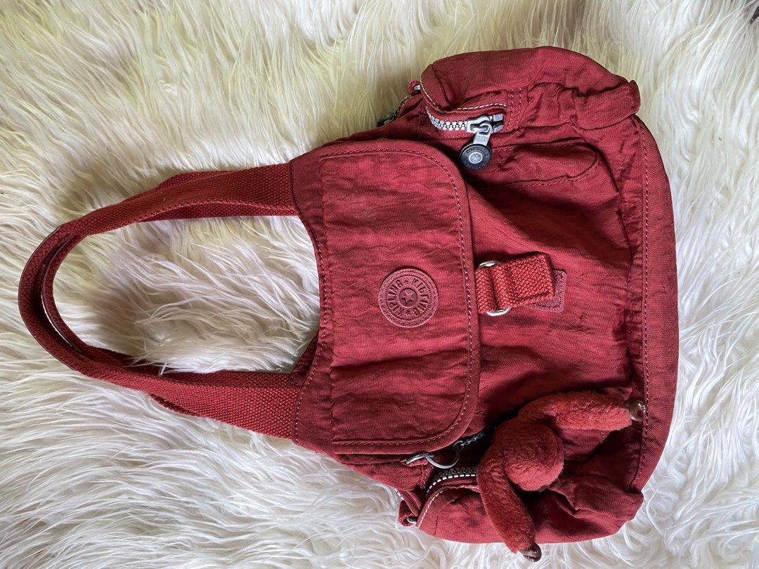 Kipling Fairfax Red Shoulder Bag K13655-108 (Category: Shoulder Bags) located in Manila. Submitted by kimberlyma95836 (Listing ID 1466412975, Image 1). Description: - Brand: Kipling - Style: Fairfax Shoulder Bag (Style Code: K13655-108) - Color: Dark Red - Material: Classic crinkle nylon with durable woven handles - Compartments: Dual main zip compartments with light grey lining - Pockets: Front flap pocket with hook-and-loop closure, plus top an