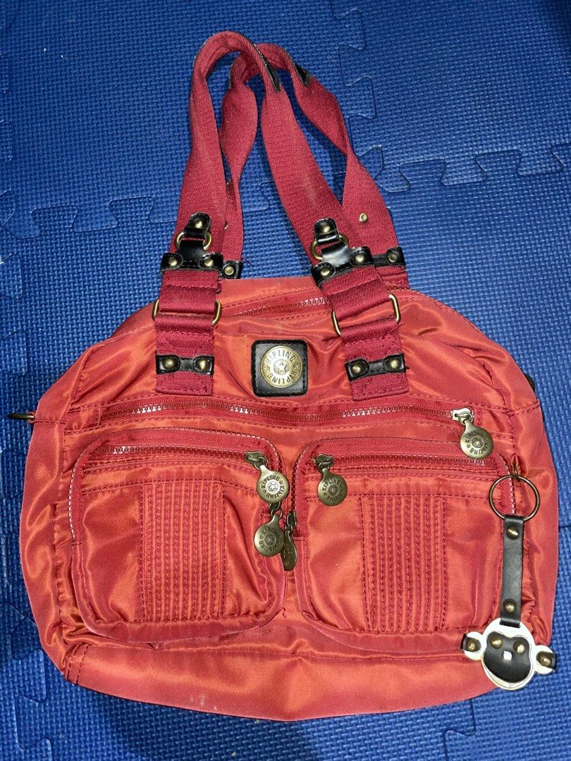 Kipling Red Nylon Shoulder Bag with Multiple Pockets (Category: Luxury Bags & Wallets) located in Baguio. Submitted by melody_tree (Listing ID 1466470615, Image 1). Description: - Brand: Kipling - Color/Material: Red nylon with black leather straps - Hardware: Metallic accents - Exterior: 2 front zippered compartments + attached coin-style keyring - Interior: Patterned fabric lining with 1 zip pocket and slip pockets - Condition: Minor wear on th