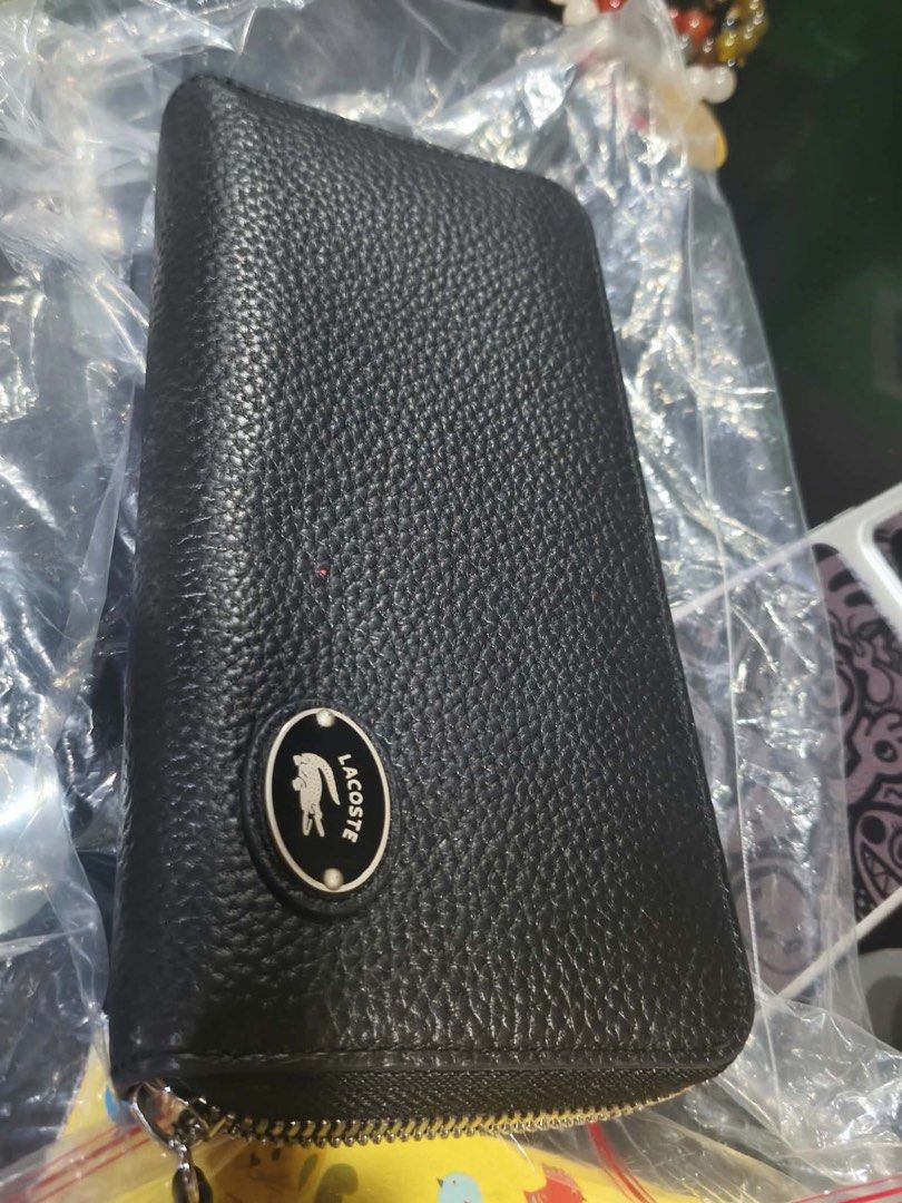 Lacoste Black Zip Around Wallet (Category: Wallets & Card holders) located in Quezon City. Submitted by prelovedbykg_ (Listing ID 1466375879, Image 2). Description: - Brand: Lacoste - Material: Premium black pebble leather - Hardware: Silver-tone with secure zip-around closure - Interior: Multiple card slots, spacious compartments, and a zippered coin pocket - Condition: Brand new - 100% authentic and ready to ship!.
