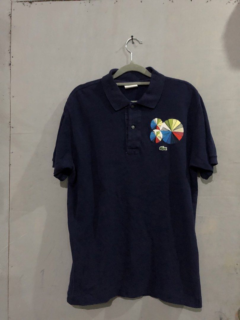 Lacoste Celebrating Eighty Polo Shirt Navy Size 4 (Category: Tshirts & Polo Shirts ) located in Magsaysay. Submitted by ryns_thrifting (Listing ID 1466356836, Image 1). Description: - Brand: Lacoste (Celebrating Eighty Collection) - Color: Navy Blue - Size: Tagged Size 4 - Details: Multi-color geometric pie chart embroidery above the classic green crocodile logo - Closure: Standard two-button placket - Condition: Clean and well-maintained overall