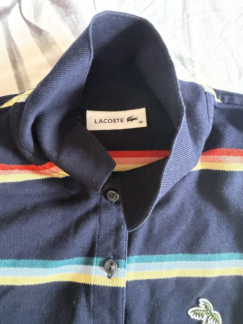 Lacoste Navy Striped Polo Shirt (Category: Tshirts & Polo Shirts ) located in Quezon City. Submitted by tancloset6 (Listing ID 1466412030, Image 2). Description: - Brand: Lacoste - Size: 36 - Color: Navy blue with red, yellow, and turquoise horizontal stripes - Material: Soft and comfortable cotton knit - Design: Short sleeves, 3-button placket, high collar design - Special Detail: Rare embroidered crocodile logo with a palm tree design - Conditi