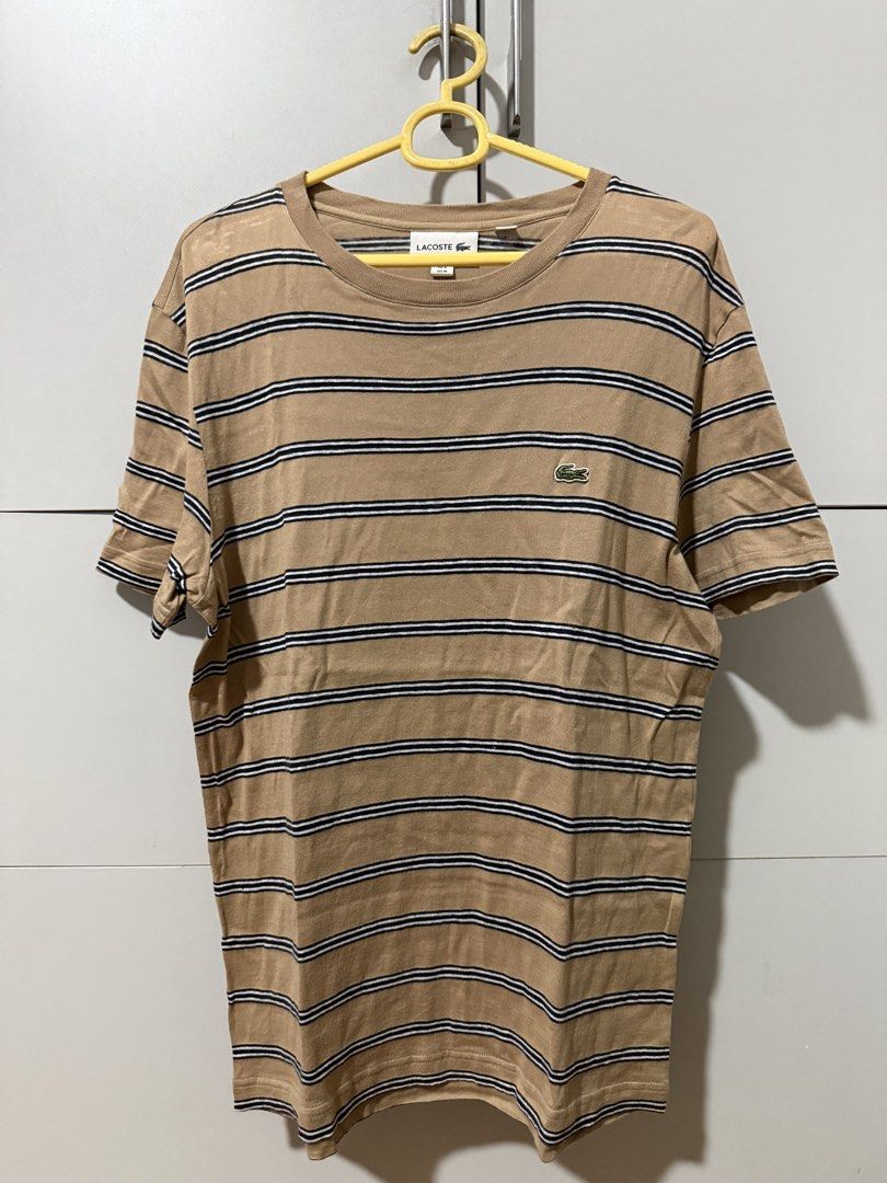 Lacoste Striped T-Shirt (Category: Tshirts & Polo Shirts ) located in Manila. Submitted by mpt99876 (Listing ID 1466520921, Image 2). Description: - Classic tan t-shirt - Features navy and white stripes - Iconic Lacoste crocodile logo on chest - Comfortable and casual design - Short sleeves and crew neck - Versatile for pairing with jeans or shorts.
