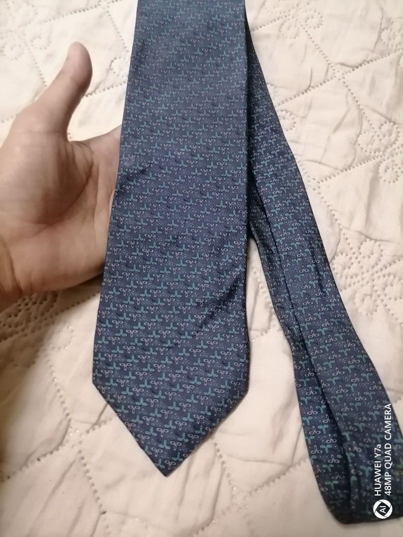 Lancel Paris Blue Patterned Silk Tie (Category: Ties) located in Naga. Submitted by mrwisethrifter (Listing ID 1466369457, Image 3). Description: Lancel Paris tie in dark blue. Pattern features small teal and grey geometric motifs all over. Made in France from 100% silk. Soft fabric with a clean drape. Brand tag stitched on the back loop. Standard width, ready to wear for work or formal events..