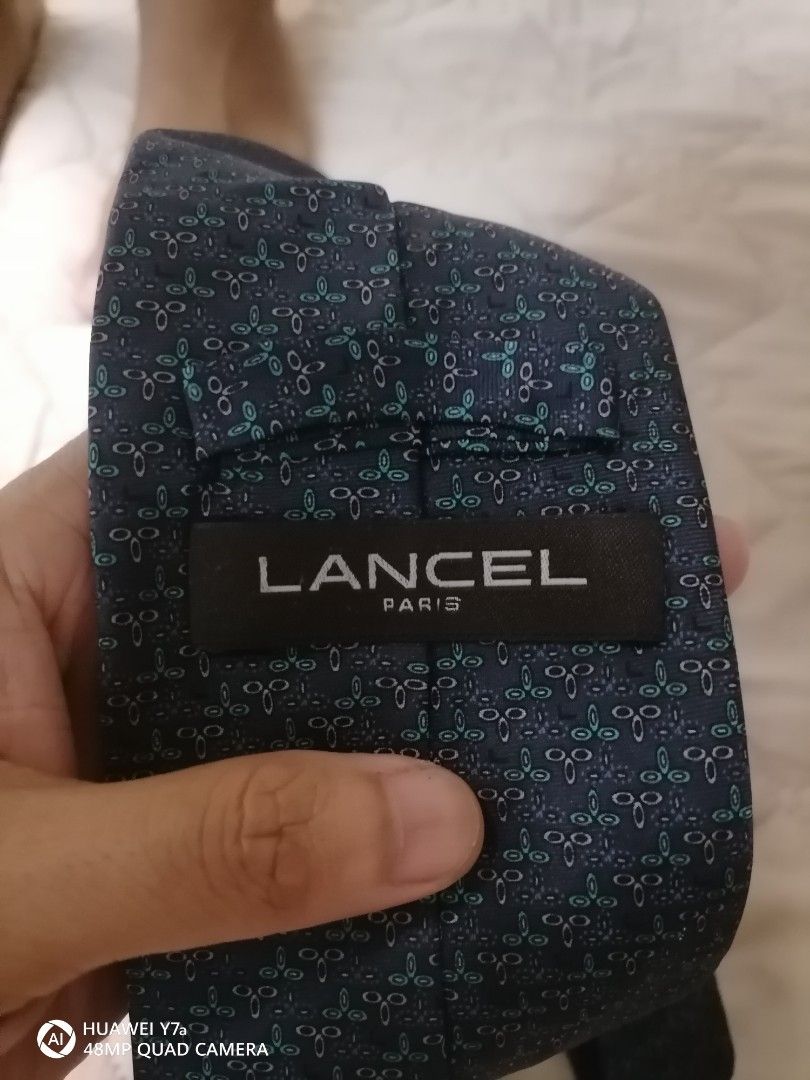Lancel Paris Blue Patterned Silk Tie (Category: Ties) located in Naga. Submitted by mrwisethrifter (Listing ID 1466369457, Image 2). Description: Lancel Paris tie in dark blue. Pattern features small teal and grey geometric motifs all over. Made in France from 100% silk. Soft fabric with a clean drape. Brand tag stitched on the back loop. Standard width, ready to wear for work or formal events..