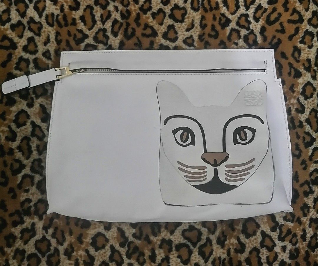 Loewe White Cat Leather Pouch Clutch (Category: Clutches) located in Cebu City. Submitted by roadthrift (Listing ID 1466506576, Image 1). Description: White leather pouch from Loewe. Features a playful cat face graphic patch on the front with embossed anagram logo. Zip top closure with a white leather zipper pull. Black edge-dye finish along the side seams and bottom gusset. Clean interior and structured rectangular shape..