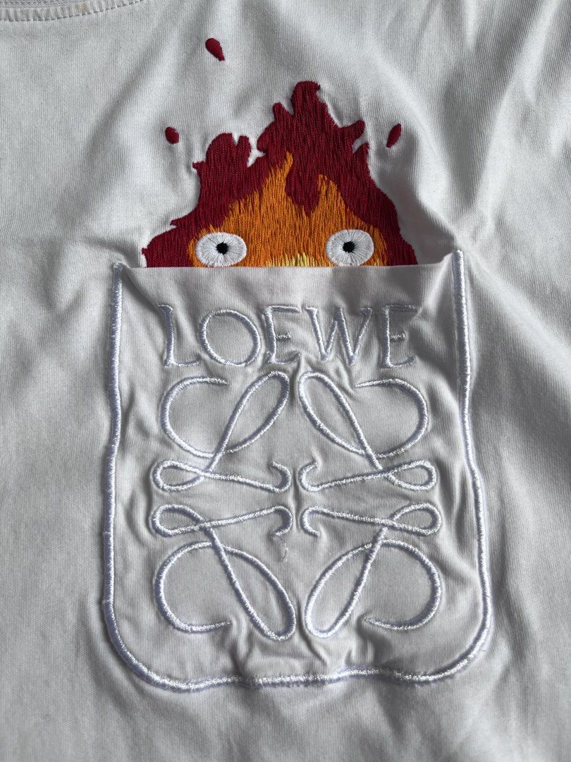 LOEWE X STUDIO GHIBLI 🔥 (Category: Tshirts & Polo Shirts ) located in Bacolod City. Submitted by johnkiercabungcal09 (Listing ID 1466391702, Image 3). Description: LOEWE x Studio Ghibli 🔥 Calcifer Peek-a-Boo Tee Size: S on tag (fits M) Dimes: 19.5” Width x 26” Length Condition: 9.5/10 - Excellent, no cracks / fade Detail: Full embroidery Calcifer, embroidered Anagram pocket Tags: Complete (Loewe + Ghibli Totoro tag + wash tag) Made in Portugal 