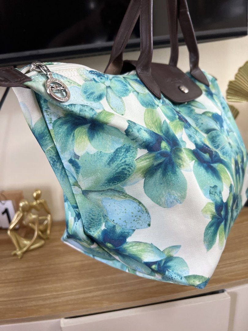 Longchamp Floral Tote Bag (Category: Luxury Bags & Wallets) located in Cauayan City . Submitted by best_buyph_88 (Listing ID 1466359822, Image 3). Description: - Authentic Longchamp tote bag with eye-catching blue and green orchid print - Dark brown leather handles and flap closure with secure snap button - Top zipper closure featuring the signature circular metal pull - Durable canvas body with clean corners and a sturdy base - Spacious interior