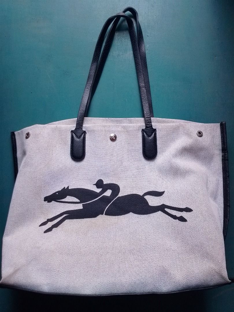 Longchamp Paris Canvas Tote Bag (Category: Tote Bags) located in Caloocan City. Submitted by hmm_shop83 (Listing ID 1466436200, Image 1). Description: - Authentic Longchamp Paris tote bag - Cream mesh-like woven canvas body with striking black leather handles and trim - Large bold logo printed across the front - Open top design with secure snap button closure - Organized interior featuring a zippered pocket and slip pockets - Clean interior linin