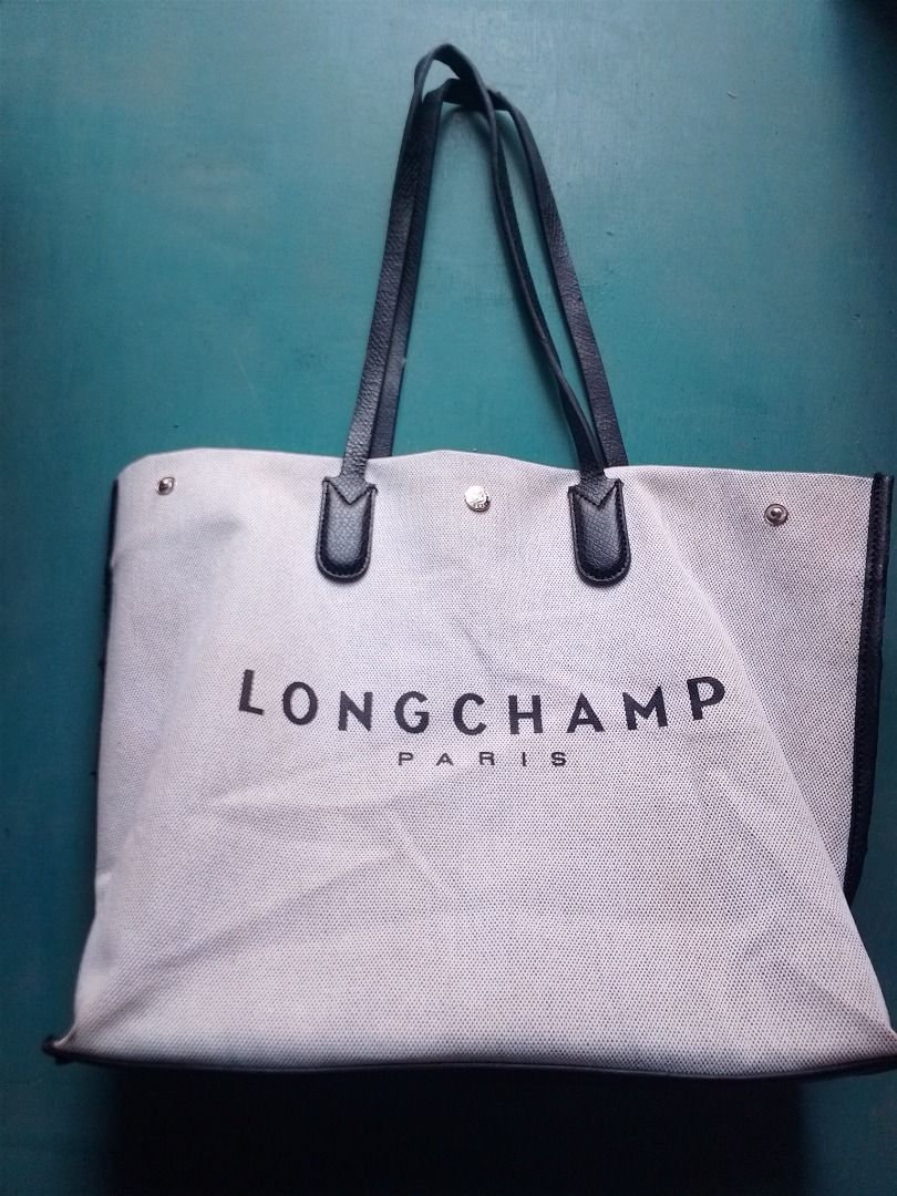 Longchamp Paris Canvas Tote Bag (Category: Tote Bags) located in Caloocan City. Submitted by hmm_shop83 (Listing ID 1466436200, Image 2). Description: - Authentic Longchamp Paris tote bag - Cream mesh-like woven canvas body with striking black leather handles and trim - Large bold logo printed across the front - Open top design with secure snap button closure - Organized interior featuring a zippered pocket and slip pockets - Clean interior linin