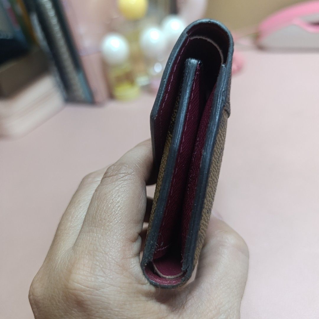 Louis Vuitton Monogram Tri-Fold Wallet (Category: Luxury Bags & Wallets) located in Las Pinas. Submitted by min_yanna (Listing ID 1466483744, Image 3). Description: Given to me a sa gift. CANNOT GUARANTEE AUTHENTICITY. Louis Vuitton tri-fold wallet in brown monogram canvas with a contrasting dark flap. Snap closure button shows minor wear. Inside has a rich purple-pink lining, multiple card slots, and a zipped coin compartment on the side. Made i