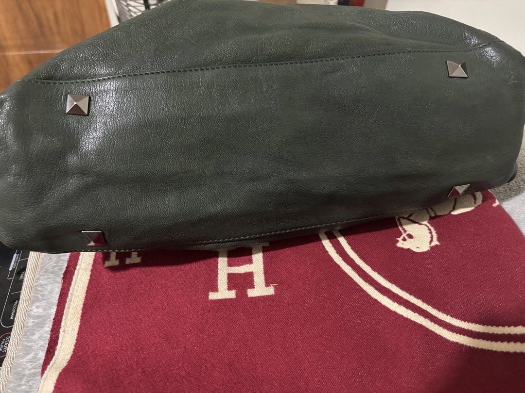 Lux & Berg dark green leather studded handbag (Category: Luxury Bags & Wallets) located in Quezon City. Submitted by mai0888 (Listing ID 1466442196, Image 3). Description: - Brand: Lux & Berg - Color/Material: Dark green leather with all-over metal pyramid studs - Handles: Comfortable rolled braided handles with matching tassel charm - Closure: Secure top zip closure - Interior: Light beige patterned lining with convenient zip and slip pockets - 