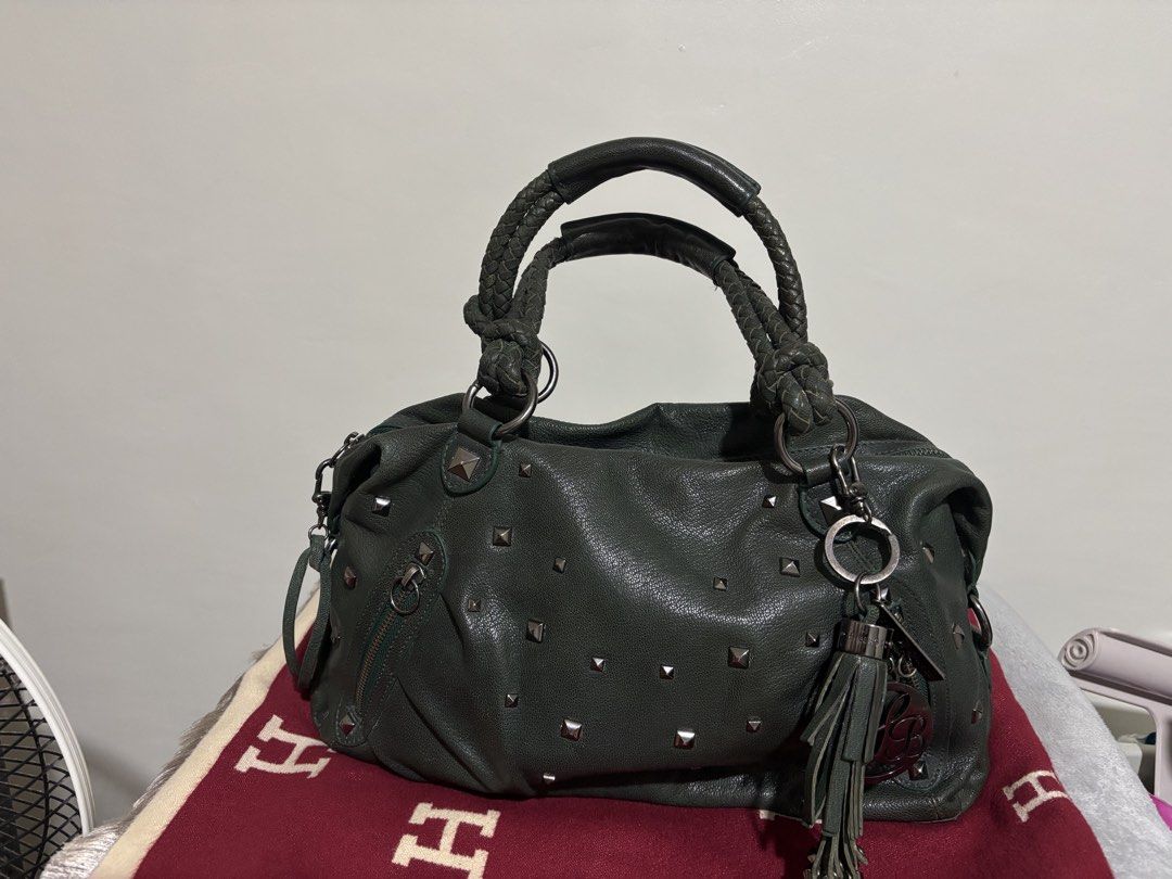 Lux & Berg dark green leather studded handbag (Category: Luxury Bags & Wallets) located in Quezon City. Submitted by mai0888 (Listing ID 1466442196, Image 1). Description: - Brand: Lux & Berg - Color/Material: Dark green leather with all-over metal pyramid studs - Handles: Comfortable rolled braided handles with matching tassel charm - Closure: Secure top zip closure - Interior: Light beige patterned lining with convenient zip and slip pockets - 