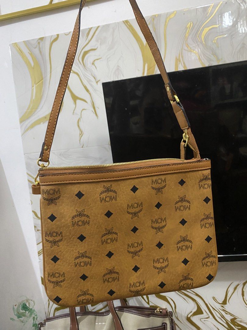 MCM Visetos Monogram Cognac Brown Shoulder Bag (Category: Luxury Bags & Wallets) located in Manila. Submitted by grandowl_5653cd (Listing ID 1466526384, Image 1). Description: Cognac brown MCM shoulder bag with classic all-over Visetos monogram print and dark diamond motifs. Gold-tone hardware with YKK zippers and engraved pull tabs. Geometric patterned fabric lining inside. Slim rectangular shape with single adjustable strap. Clean condition thr