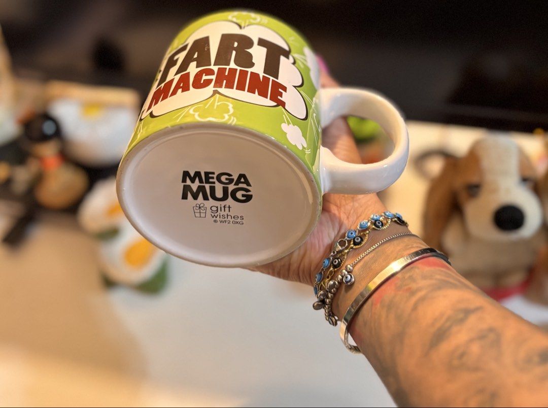 Mega Mug Fart Machine Novelty Coffee Mug (Category: Coffee & Tea Tableware) located in Bacoor. Submitted by dangeusebio1515 (Listing ID 1466541877, Image 3). Description: - Hilarious novelty mug featuring a 'Fart Machine' graphic on a bright green background with comic-style cloud details - Designed with a comfortable large white ceramic handle and interior - Authentic 'Mega Mug by Gift Wishes' stamp on the bottom - Perfect gag gift for coworkers