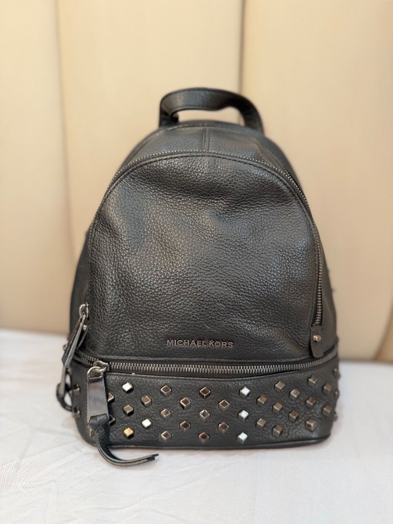 Michael Kors Black Studded Leather Backpack (Category: Backpacks) located in Rizal. Submitted by je_resada (Listing ID 1466345116, Image 1). Description: - Black pebbled leather backpack - Chic silver-tone metal studs along the bottom - Front zip pocket and sturdy top handle - Interior lined with convenient slip pockets - Compact size, perfect for everyday carry - 100% working smooth zipper closures.