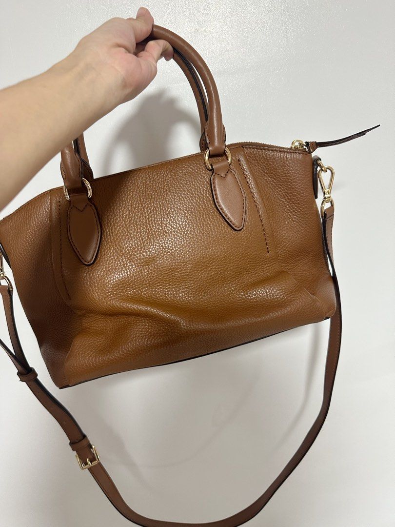 Michael Kors Brown Leather Satchel Bag (Category: Luxury Bags & Wallets) located in Orion. Submitted by ycahandres (Listing ID 1466458051, Image 2). Description: - Brand: Michael Kors - Material: Premium tan pebbled leather - Hardware: Elegant gold-tone - Closure: Secure top zip - Versatile Carry: Dual top handles and a detachable, adjustable crossbody strap - Structure: Structured design with protective metal feet - Interior: Fabric-lined with h