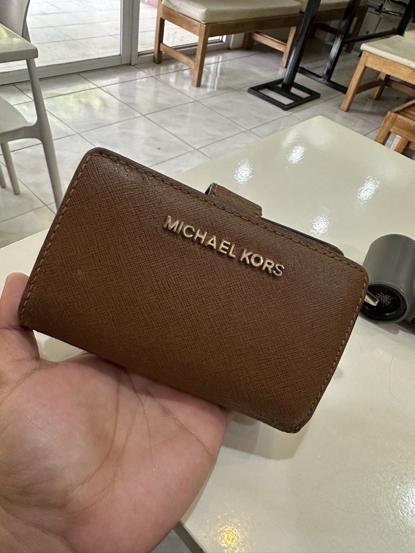 Michael Kors Brown Saffiano Leather Wallet (Category: Wallets & Card holders) located in Cauayan City . Submitted by sherinejoy_ (Listing ID 1466403497, Image 1). Description: - Authentic Michael Kors wallet - Material: Premium brown Saffiano leather - Closure: Secure snap button - Interior: Multiple card slots with signature MK logo lining - Size: Compact design fits easily into any handbag - Color: Classic tan brown that matches any outfit.