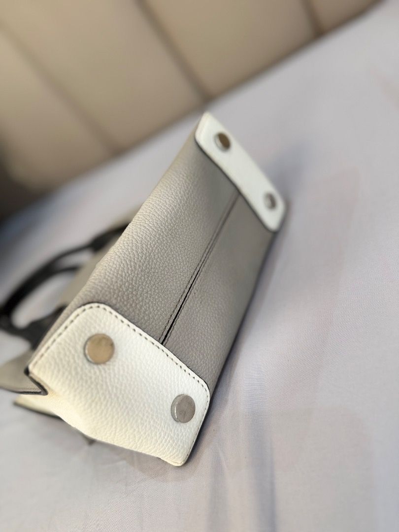 Michael Kors Mercer Tote Bag (Category: Tote Bags) located in Rizal. Submitted by je_resada (Listing ID 1466344793, Image 2). Description: - Brand: Michael Kors - Color: Cream pebble leather with black top handles - Hardware: Silver-toned with dangling padlock charm - Features: Detachable crossbody strap, secure zip compartment inside, and card slots - Condition: Clean interior, bottom feet intact, and minor signs of wear on the handles - Style: 